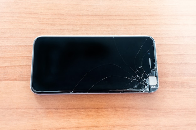 Foto vidrio roto de teléfono inteligente en la mesa de madera