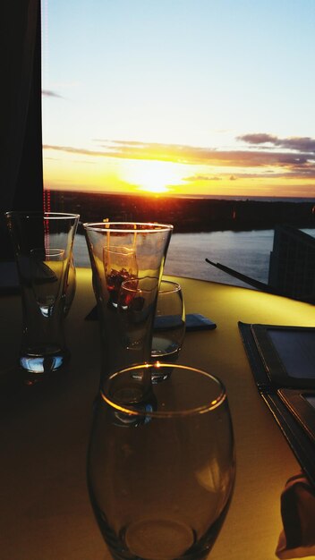 Foto vidrios brillantes en la mesa contra el cielo durante la puesta de sol