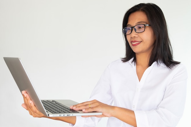 Vidrios que llevan de la mujer de negocios que sostienen el cuaderno de Labtop en el fondo blanco