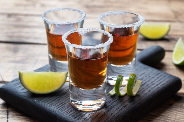 Vidro com álcool, sal e limão em uma mesa de madeira