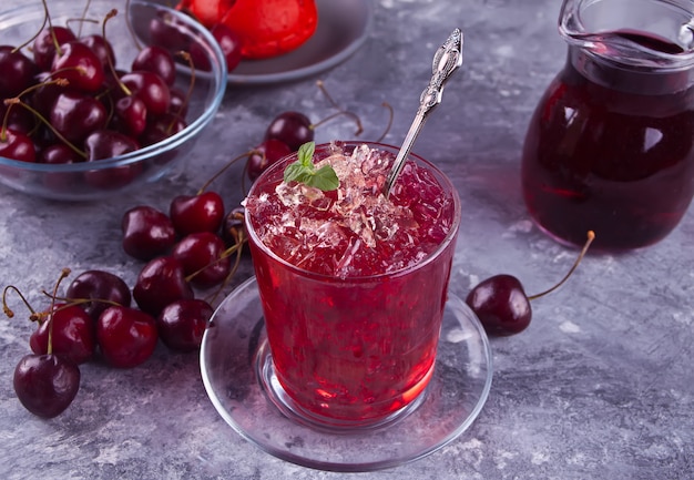 Vidro com chá gelado doce da cereja caseiro fresca ou cocktail, limonada com hortelã. Refrescante bebida gelada. Festa de Verão.