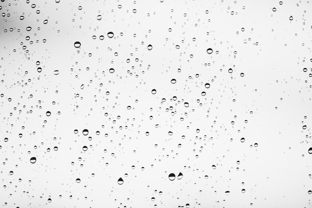 Vidro da janela suja com gotas de chuva. atmosférico monocromático luz de fundo com pingos de chuva. gotas e manchas de perto. textura transparente detalhada em macro com espaço de cópia.