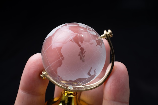 Vidro de cristal do globo mundial na mão Negócios e economia globais Conceito ambiental ou ecológico