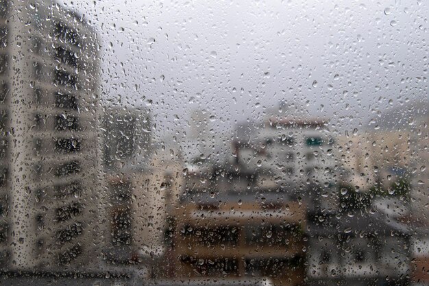 vidro de janela com gotas de chuva mostrando a cidade desfocada ao fundo