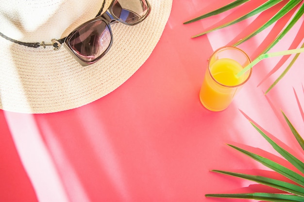 Vidro de óculos de sol de chapéu de palha com folhas de palmeira de suco de frutas tropicais frescas
