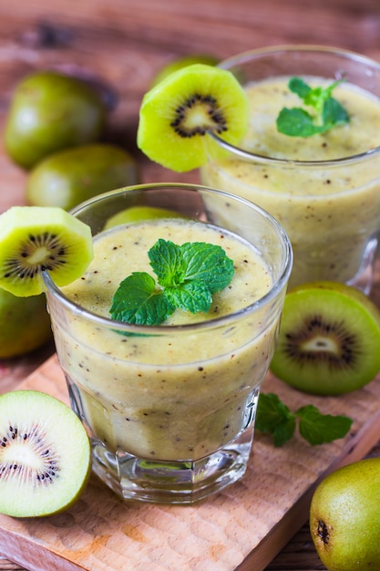 Vidro de suco de kiwi com frutas frescas na mesa de madeira