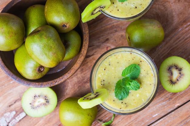 Vidro de suco de kiwi com frutas frescas na mesa de madeira