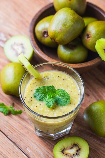 Vidro de suco de kiwi com frutas frescas na mesa de madeira