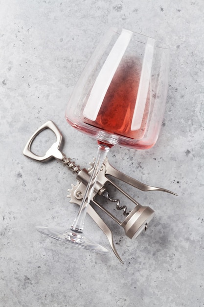 Vidro de vinho tinto e saca-rolhas em pano de fundo de pedra Vista superior