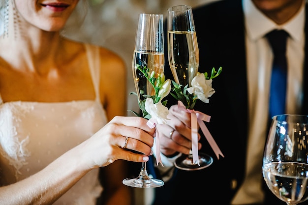 Vidro decorado com flores e vegetação no fundo os recém-casados fecham A noiva e o noivo seguram taças de champanhe em suas mãos Cerimônia de casamento