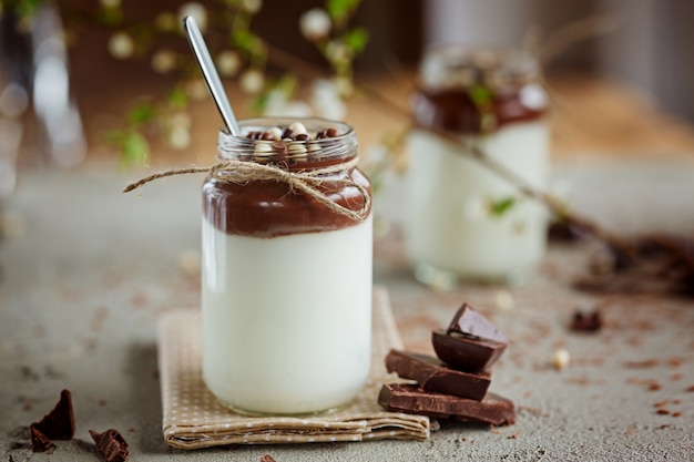 Foto vidro do iogurte caseiro com musse de chocolate e doces e colher de chocolate.