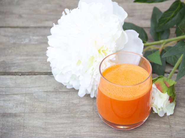 Vidro do suco de cenoura alaranjado no espaço de madeira da cópia gratuita.