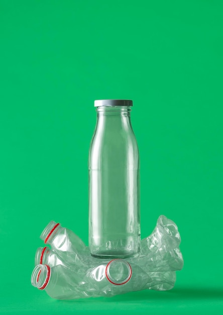 Vidro sobre o conceito de garrafas plásticas em um fundo verde