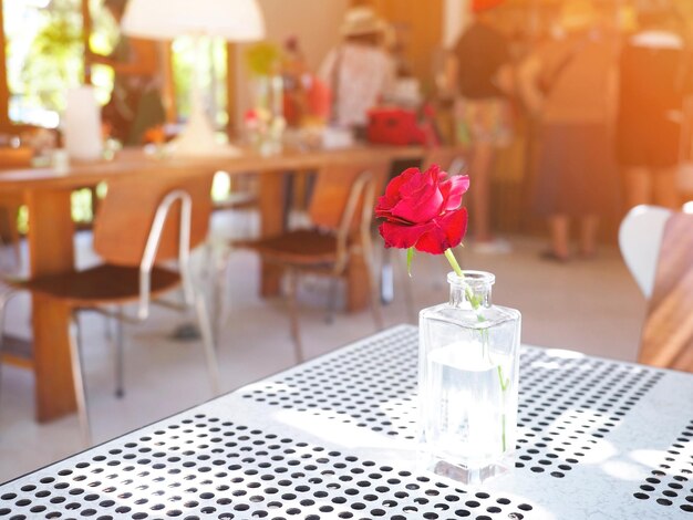 Foto vidro transparente de rosa vermelha na mesa da cafeteria