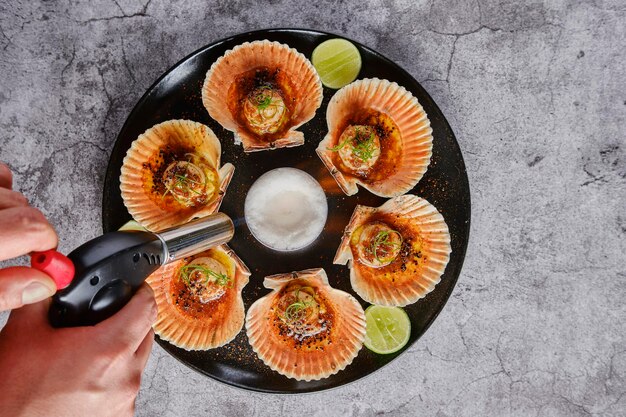 Vieiras con conchas flameadas en un plato negro Comida de restaurante de lujo Mariscos