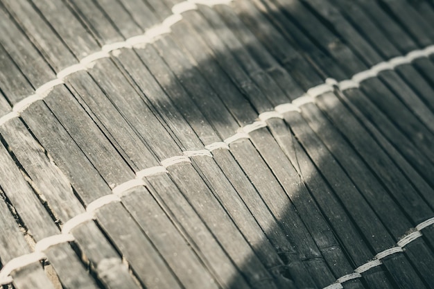 Vieja alfombra de bambú tejida textura áspera banner de fragmento sucio Líneas verticales horizontales diagonales sombra de contraste Espacio de copia para texto Fondo abstracto Tonos de gris amarillento marrón claro más en stock