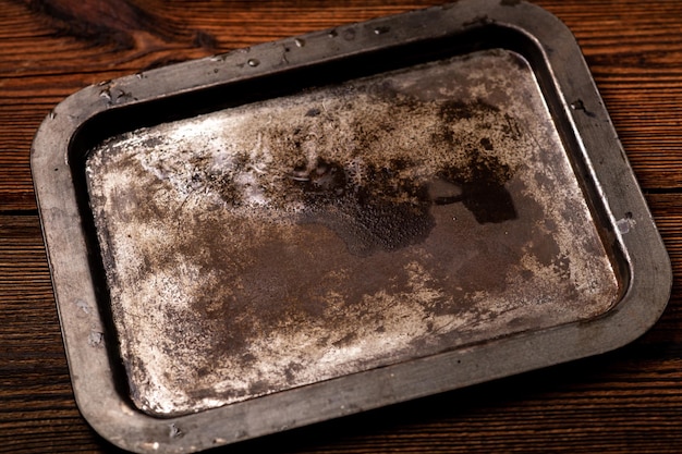 Vieja bandeja de acero oxidado sobre un fondo de madera oscura Lugar para el texto