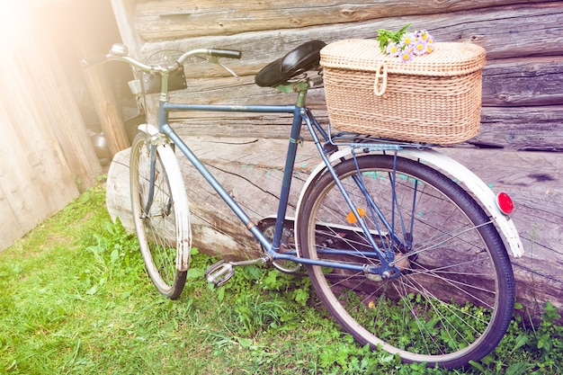 Una vieja bicicleta con una canasta de flores en el jardín de la aldea