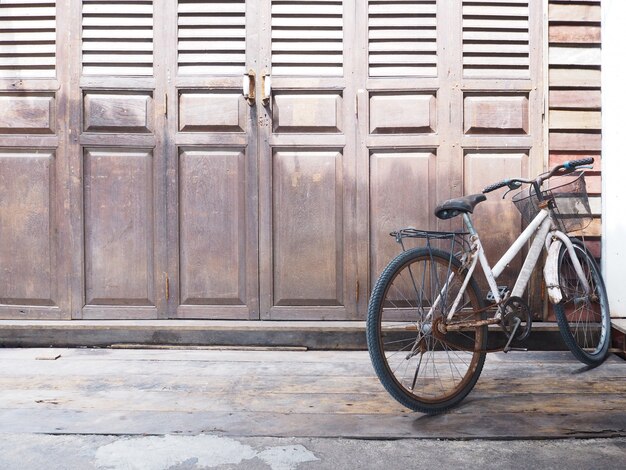 Vieja bicicleta de estacionamiento en frente de la puerta de madera vintage