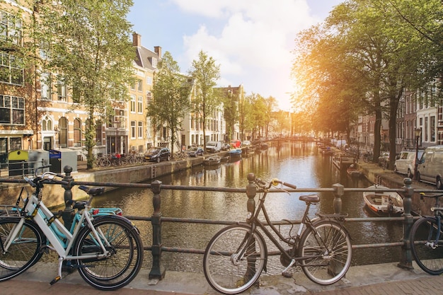 Vieja bicicleta en el puente en Amsterdam Países Bajos contra un canal durante el día soleado de verano Postal vista icónica Concepto de turismo