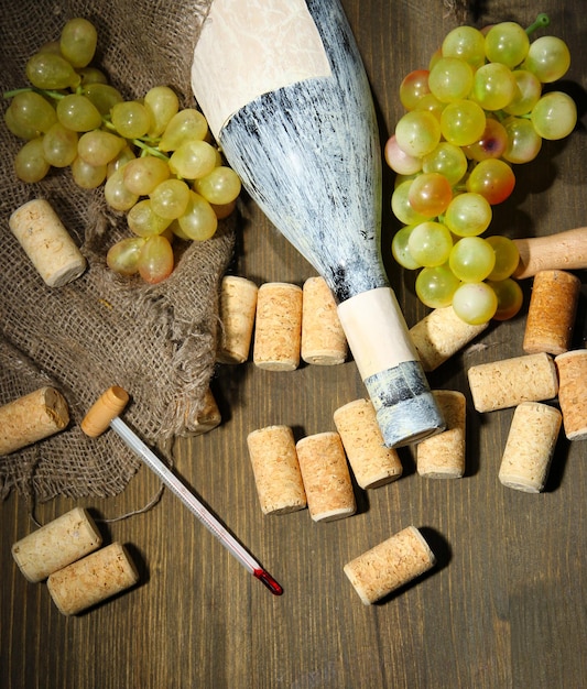Vieja botella de uvas de vino y corchos sobre fondo de madera