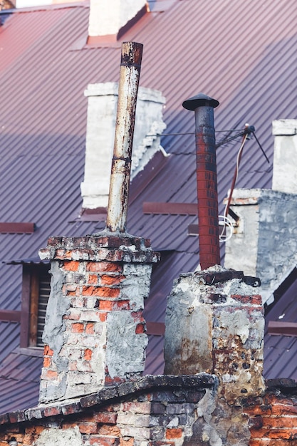 Una vieja chimenea de ladrillo con chimenea de hierro oxidado que sobresale