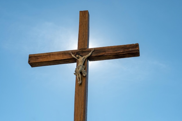 Una vieja cruz católica de madera contra el fondo del sol y el cielo azul claro Religión y servicio a Dios como camino hacia la redención del pecado El rostro de Jesús crucificado en la cruz