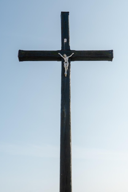 Una vieja cruz cristiana de madera contra un cielo azul claro en un hermoso día de verano Una estatuilla de Jesús en el centro de la cruz La crucifixión de Cristo La fiesta de la Pascua y la Resurrección