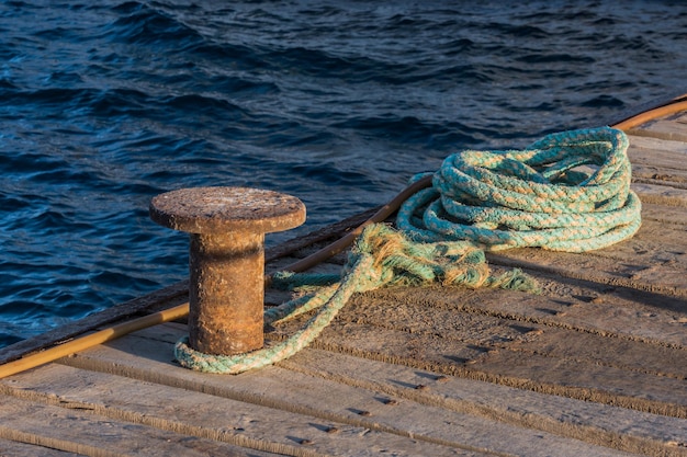 Vieja cuerda colorida con un archivo adjunto en un embarcadero en el mar