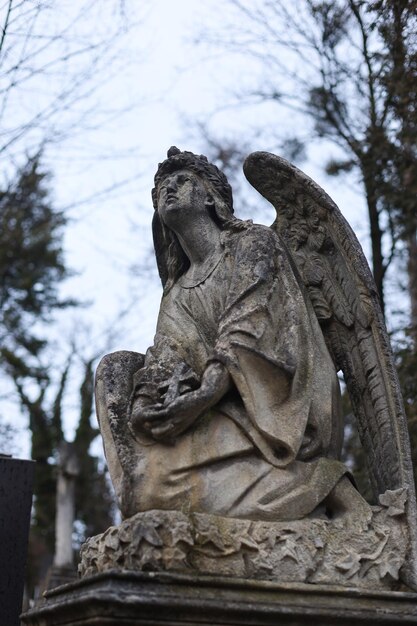 Una vieja estatua de ángel en una lápida en un cementerio o cementerio cristiano