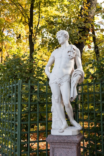 Foto la vieja estatua del parque de la sensual mujer de la época del renacimiento griego o italiano con flores en el parque de la ciudad fue a los colores dorados del otoño,