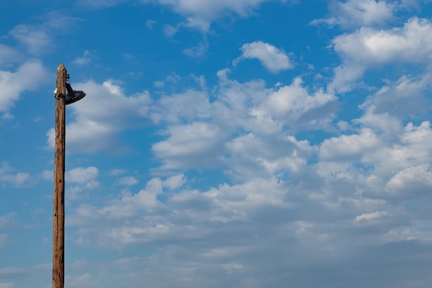 Una vieja farola de madera contra un cielo azul con nubes blancas