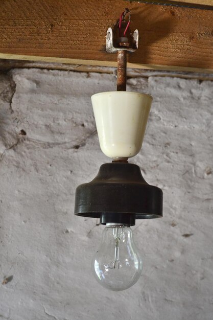 una vieja lámpara con una lámpara cuelga de una pared de madera