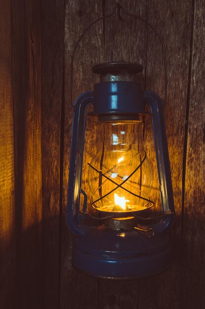 La vieja lámpara de queroseno ilumina la vieja pared de madera