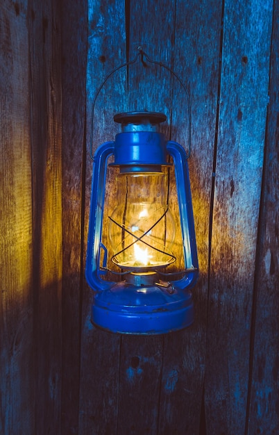 La vieja lámpara de queroseno ilumina la vieja pared de madera