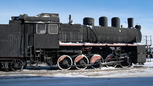 Una vieja locomotora de vapor rusa soviética negra. Equipo militar en la nieve.