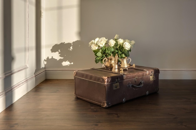 Vieja maleta vintage en el piso de una habitación vacía con un ramo de flores