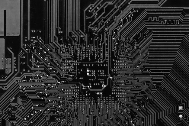 Vieja placa base de computadora negra con manchas de polvo y óxido en el fondo