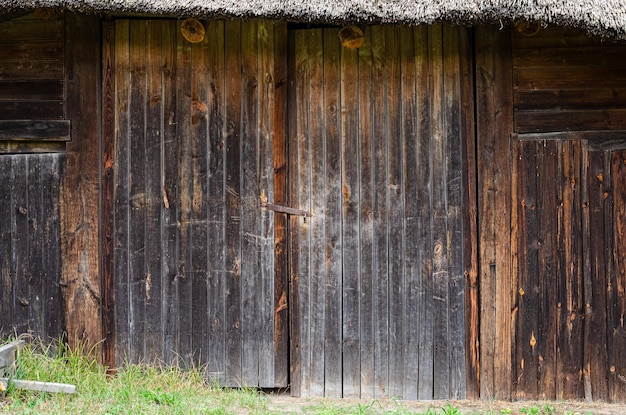 Vieja puerta desgastada en la pared de madera de una choza antigua