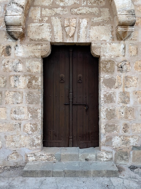 Vieja puerta de madera marrón con un engranaje de bloqueo masivo en una pared de piedra