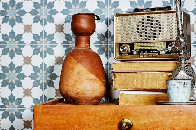 vieja radio vintage retro por encima de los libros con botella de arcilla en la mesa de madera