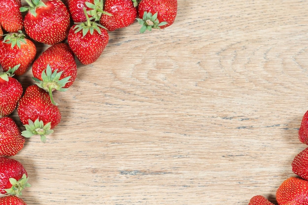 Vieja textura de madera con fresas maduras en las esquinas como fondo decorativo