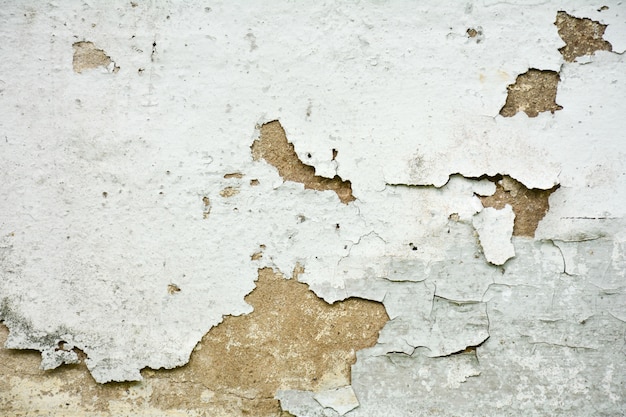 La vieja textura de pintura blanca está desconchada y agrietada en la pared.