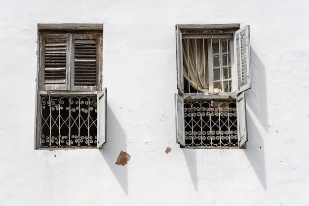 Vieja ventana con persianas de madera en la pared de estuco blanco en Stone Town en la isla de Zanzíbar, Tanzania, África