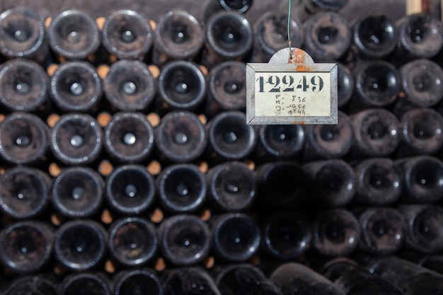 Viejas botellas de vino oscuro y polvoriento en filas en la bodega