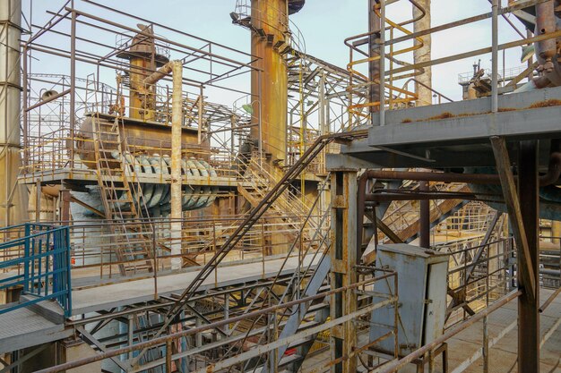 Viejas estructuras metálicas de fábrica Planta industrial con viejas tuberías oxidadas y torre de enfriamiento