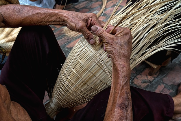 Viejas manos de artesano vietnamita manos haciendo la trampa de peces de bambú tradicional