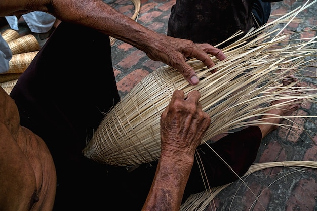 Viejas manos de artesano vietnamita manos haciendo la trampa de peces de bambú tradicional