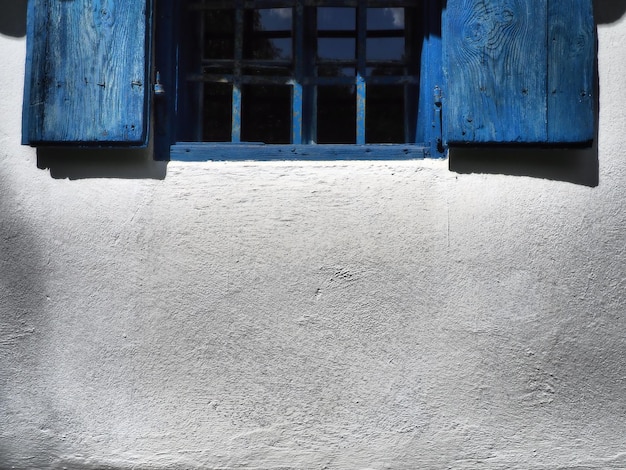 Las viejas persianas de madera están abiertas Los marcos de las ventanas de madera y las persianas están pintadas de azul