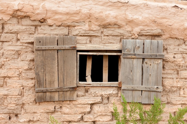 Viejas persianas de madera en la pared de ladrillos de barro